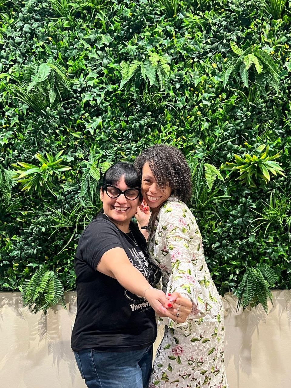 Candi and a client sharing a joyful moment before a green living wall