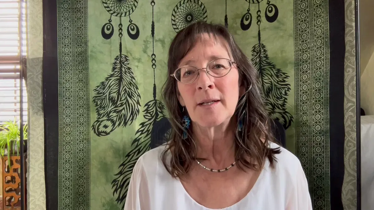 A client speaking from a calm room with a green feather tapestry